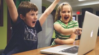 パソコンの前で大喜びする子ども